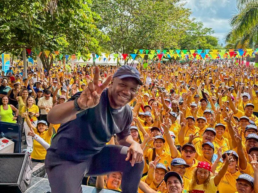 Alcalde Víctor Ramos sonriente con una camiseta verde neón y una gorra negra lidera una maratón de aeróbicos y ejercicio con musica en vivo al aire libre en Palmira.