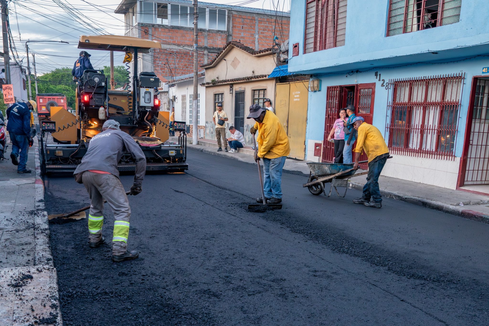 Personal operativo y maquinaria pesada realizan la pavimentación asfáltica de una calle en el barrio La Emilia, Palmira.