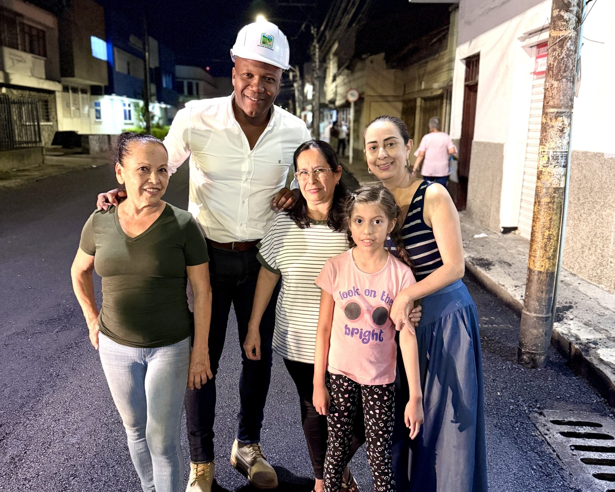 El alcalde de Palmira, Víctor Ramos, posa junto a tres mujeres y una niña en una calle recién pavimentada durante una supervisión de obra nocturna.