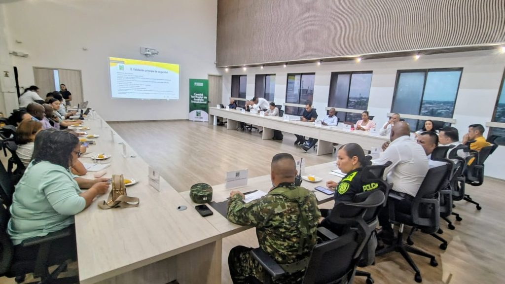 Integrantes del Comité Territorial de Justicia Transicional de Palmira, incluyendo personal de la fuerza pública y la administración municipal, reunidos en una mesa de trabajo institucional en un salón de reuniones.