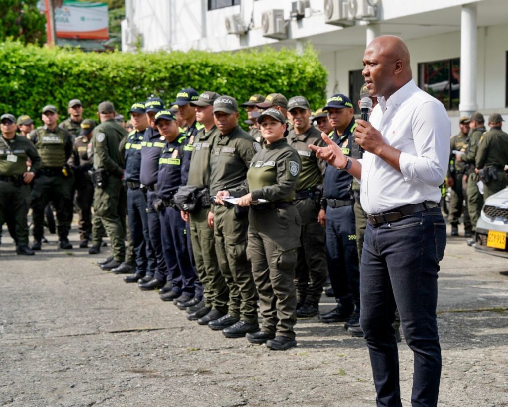 El alcalde de Palmira, Víctor Ramos, habla por micrófono frente a un grupo de integrantes de la Policía Nacional formados en filas durante un evento de seguridad.