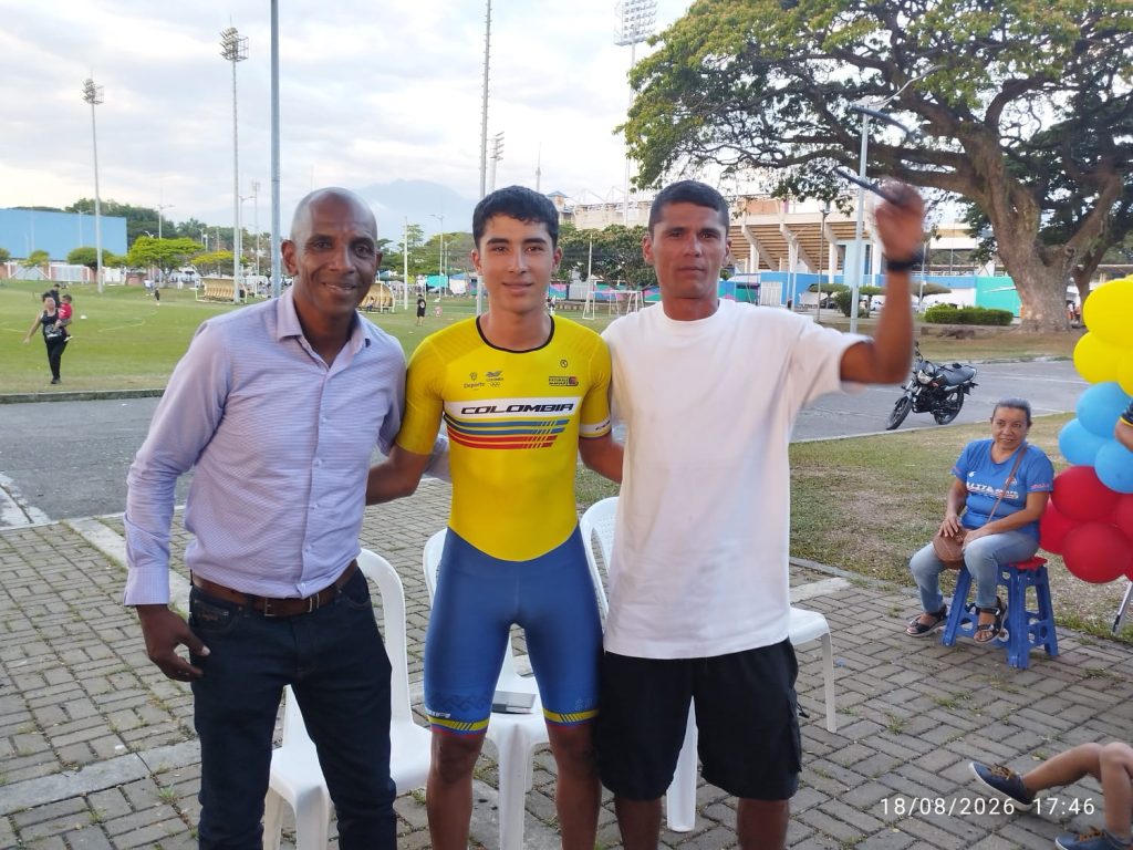 En la foto un deportista con el uniforme tricolor de la Selección Colombia de Patinaje posa sonriente en el centro, acompañado por dos hombres en una unidad deportiva de Palmira.
