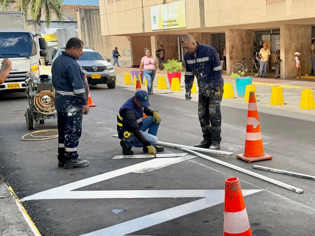 En la foto tres trabajadores de la Alcaldía realizan demarcación de señalización vial en el piso frente al Centro Integral de Atención al Ciudadano (CIAC).