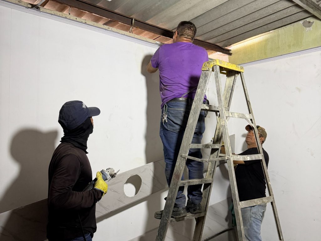 En la fotografía tres personas realizan trabajos de inspección en el techo y paredes de un espacio en obra.