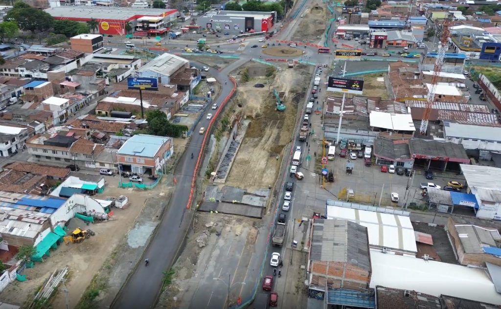 Vista aérea de la obra en construcción del deprimido de Versalles en Palmira, mostrando la excavación central, maquinaria pesada y el flujo de vehículos por los carriles laterales habilitados.