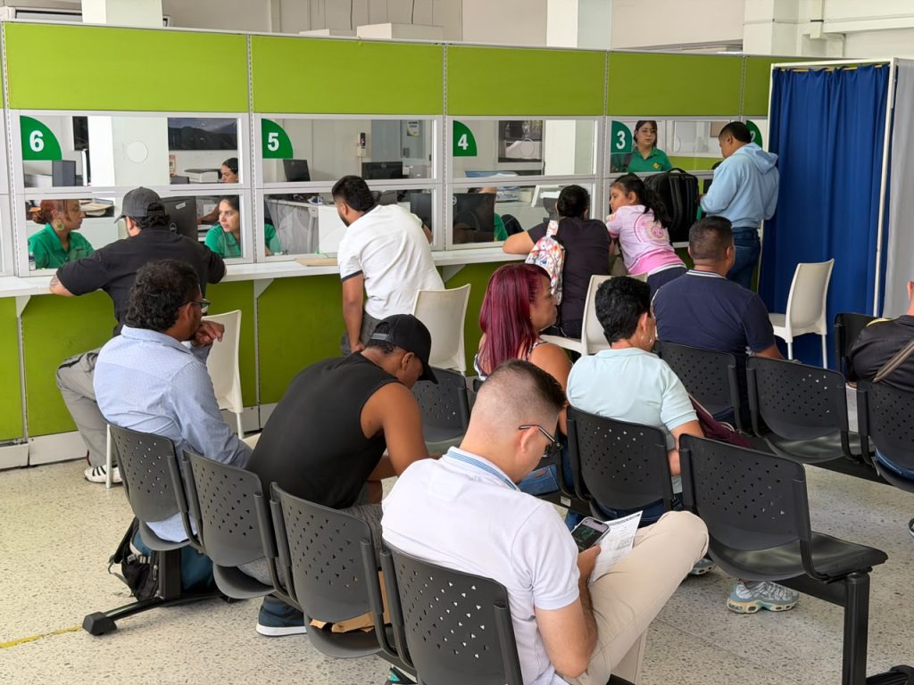 En la fotografía Personas usuarias en una sala de espera y ventanillas de atención ciudadana realizando trámites administrativos de tránsito