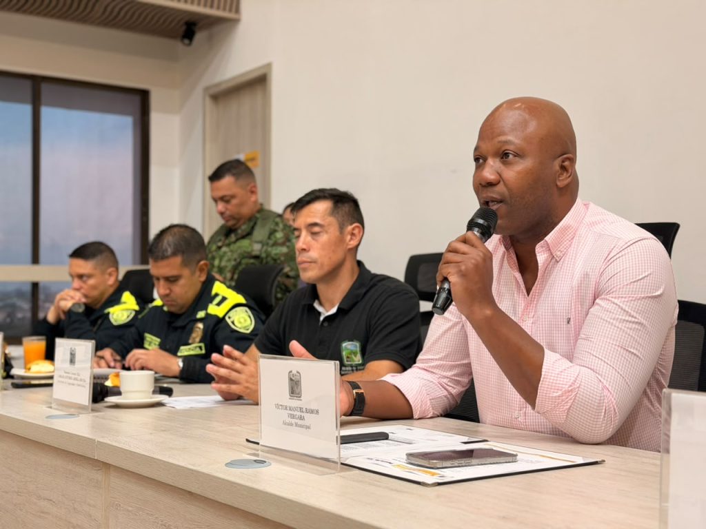 El alcalde Víctor Ramos habla por micrófono durante consejo de seguridad, acompañado en la mesa por oficiales de la Policía Nacional y del Ejército.