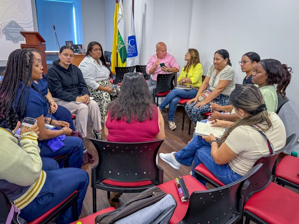 Grupo de docentes orientadores y profesionales sentados en círculo tomando notas durante un encuentro de trabajo en un auditorio universitario.