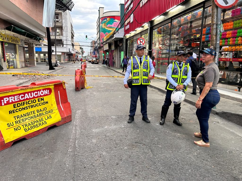 En la foto custodian un perímetro acordonado en una calle comercial con señales de precaución por obra en infraestructura.